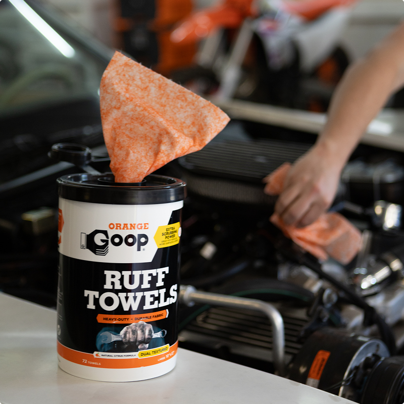 Orange goop container with wipe being used to clean an engine